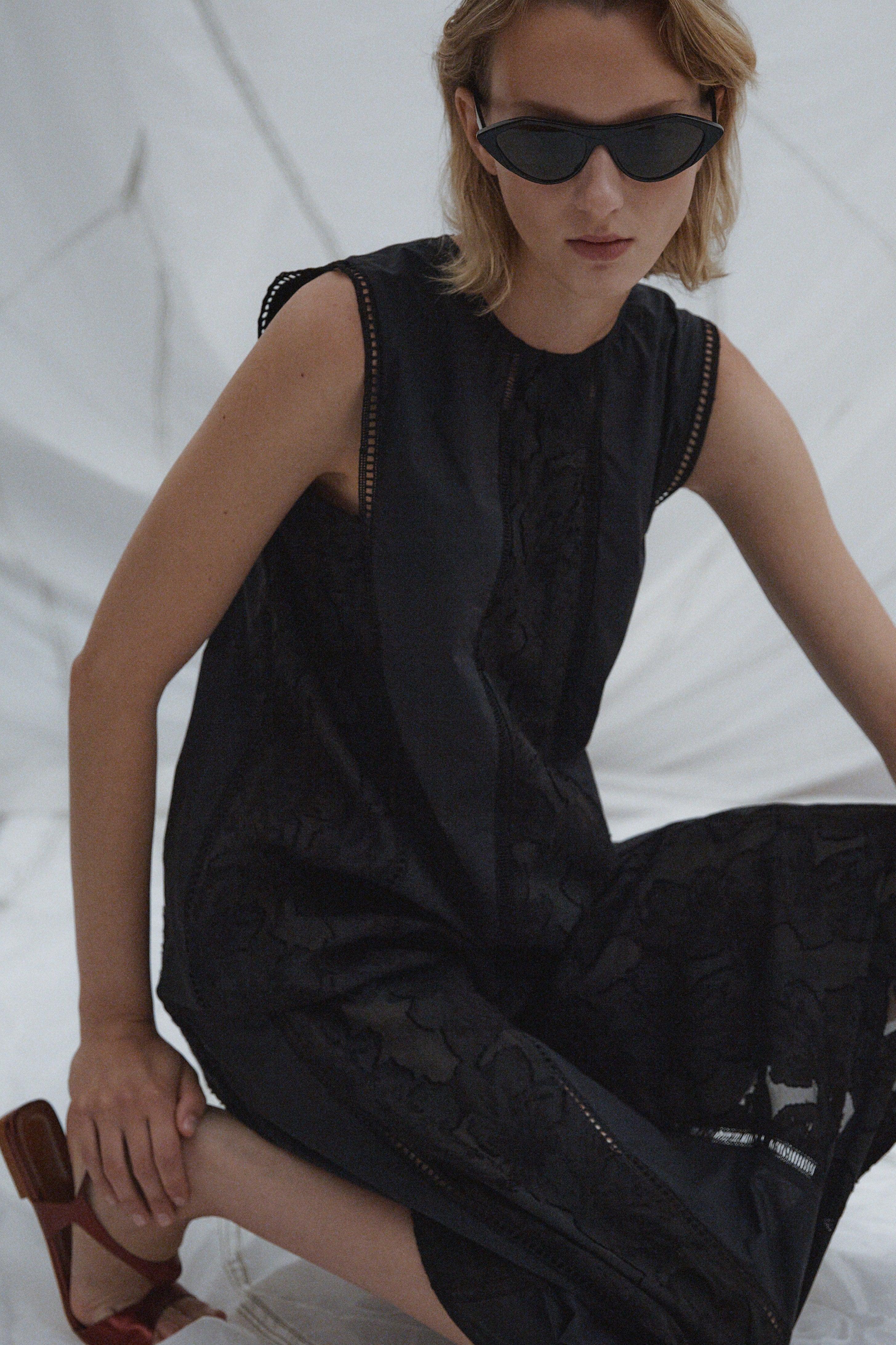 Woman wearing a Rachel Comey Spring 2026 black sleeveless dress with sunglasses against a white background